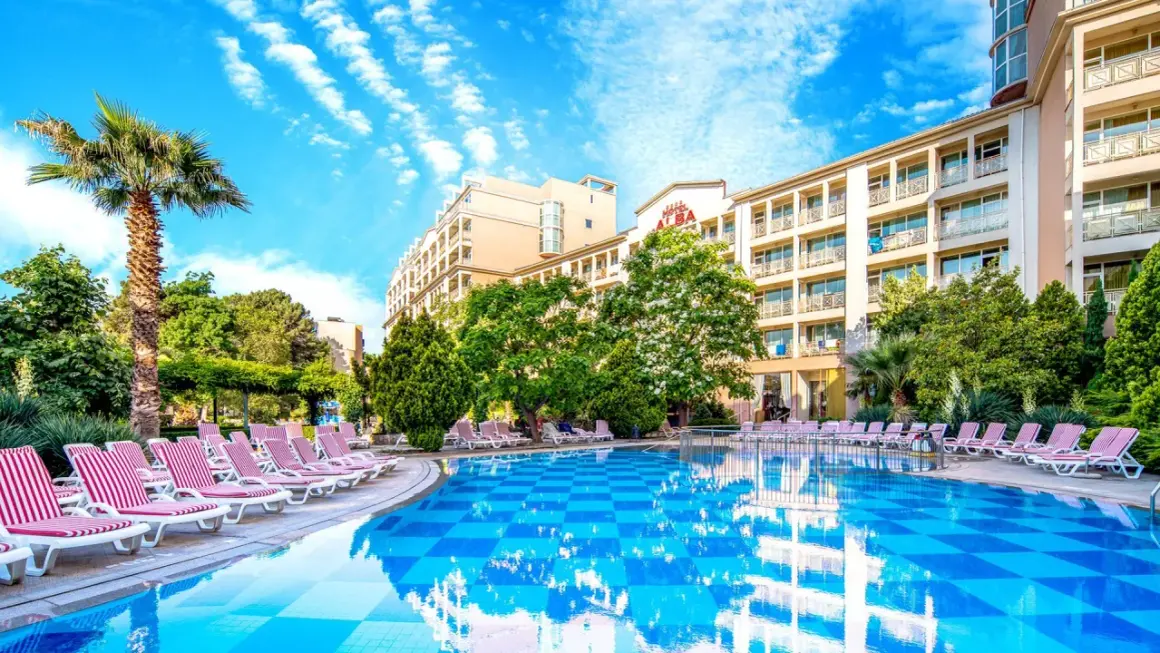 Basen i leżaki przy hotelu Alba w Bułgarii. Słoneczny dzień, błękitne niebo i palmy tworzą wakacyjny klimat.