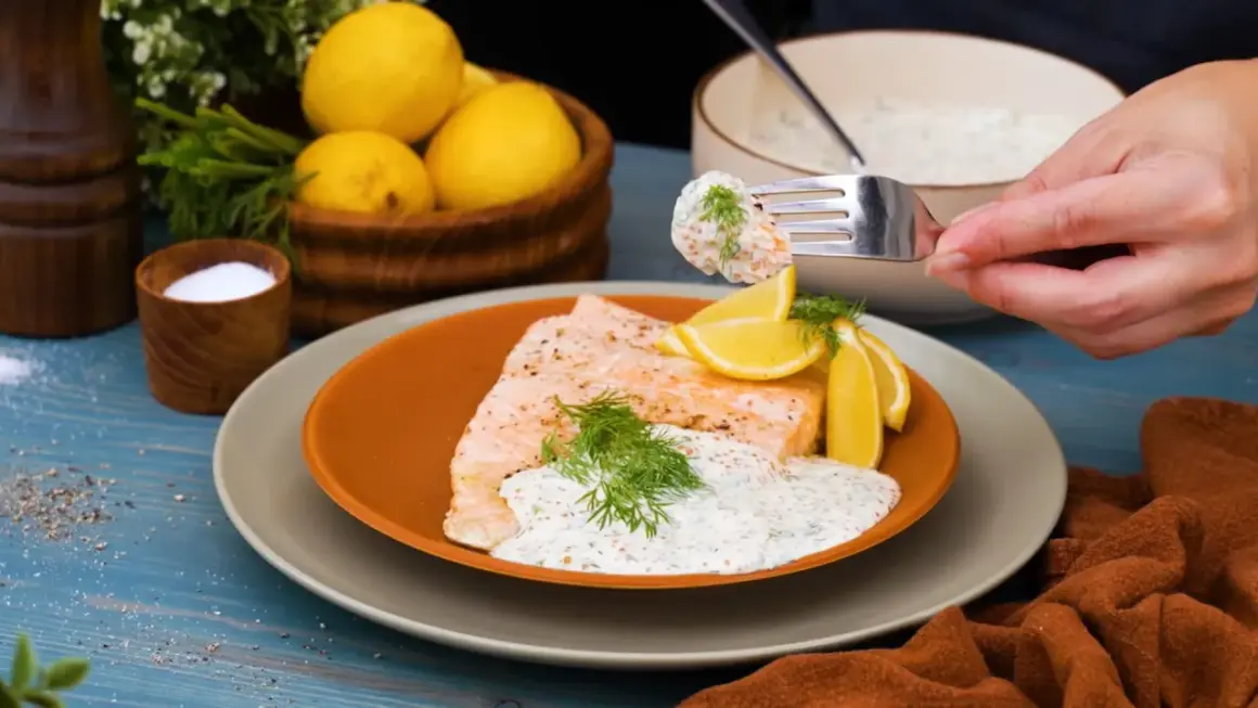 En gaffel tar en bit lax med romsås. Serverad med citron och dill.