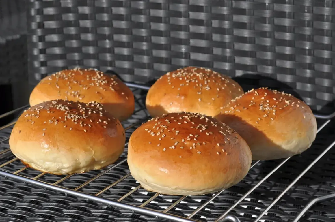 Fünf goldbraune Burgerbrötchen mit Sesam, frisch gebacken nach einem tollen burger buns rezept.