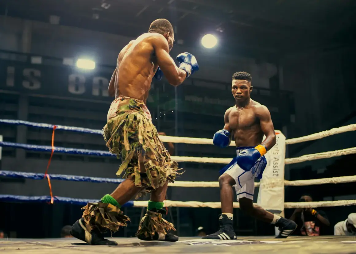 Two boxers face off in a ring, one in camouflage shorts, the other in blue. Their boxing opponent is ready for the fight.