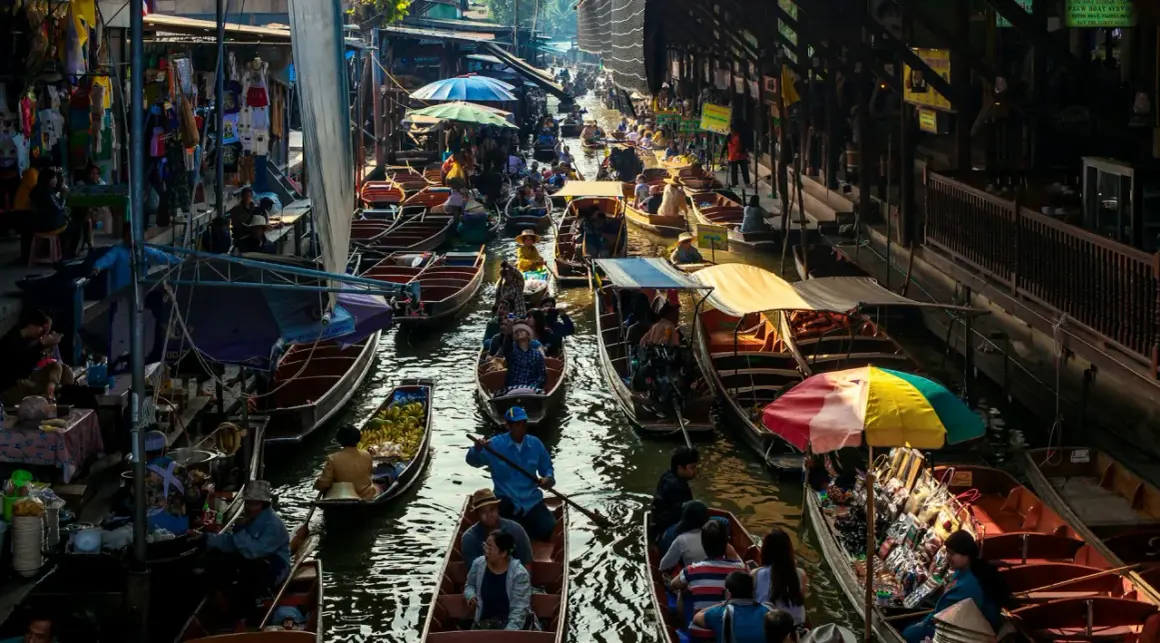 Livligt marknadsliv i Bangkok med båtar fyllda med varor och människor som navigerar på kanalen.