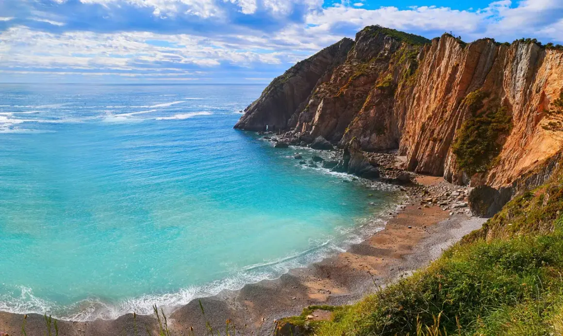 Aguas turquesas bañan la **cascada playa del Silencio**, rodeada de imponentes acantilados ocres y vegetación exuberante.