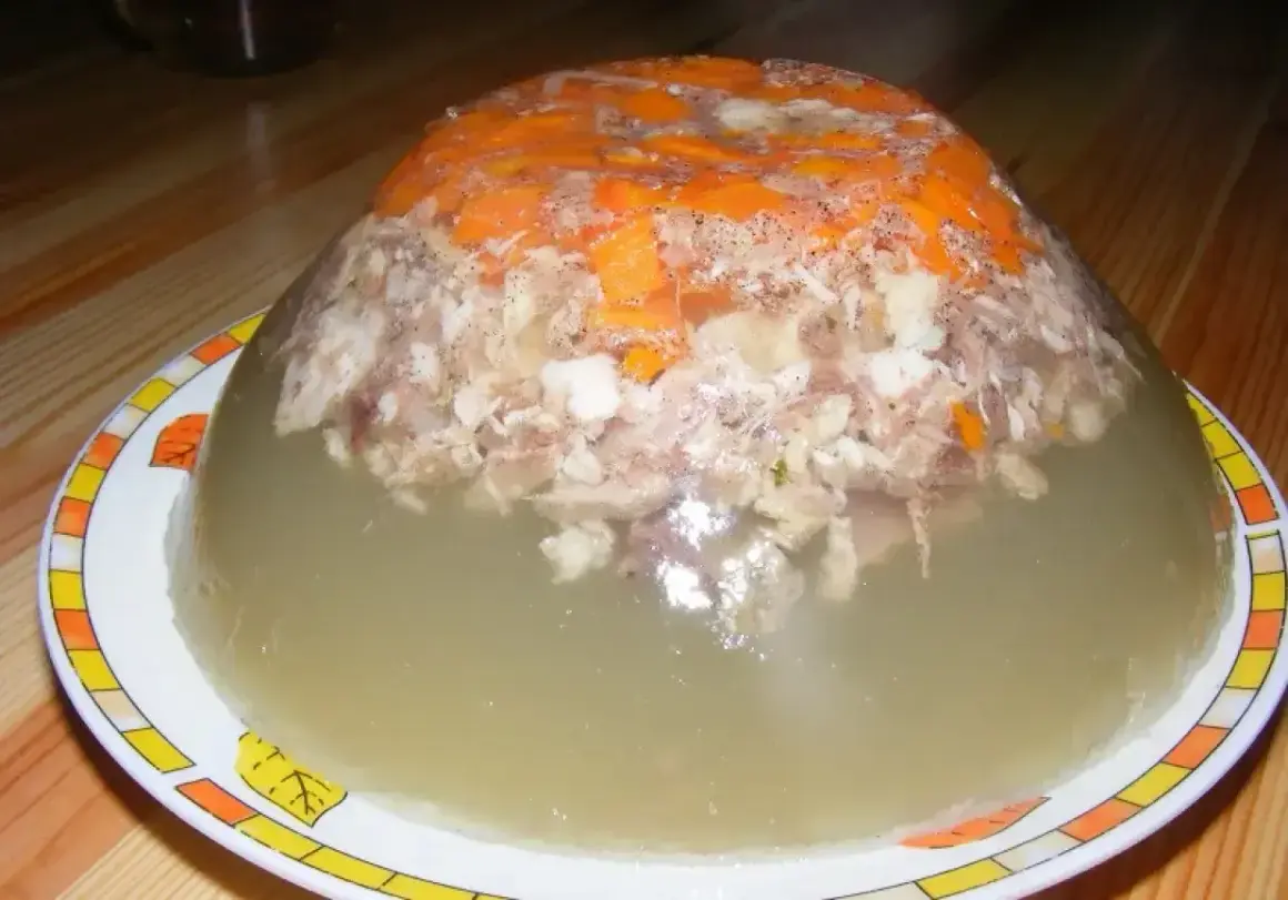 Tradycyjna galareta wieprzowa z kawałkami mięsa i marchewki, w galaretce, na talerzu.