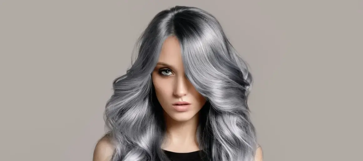 Frau mit voluminösem, welligem Haar in einem modernen balayage grau Farbton.