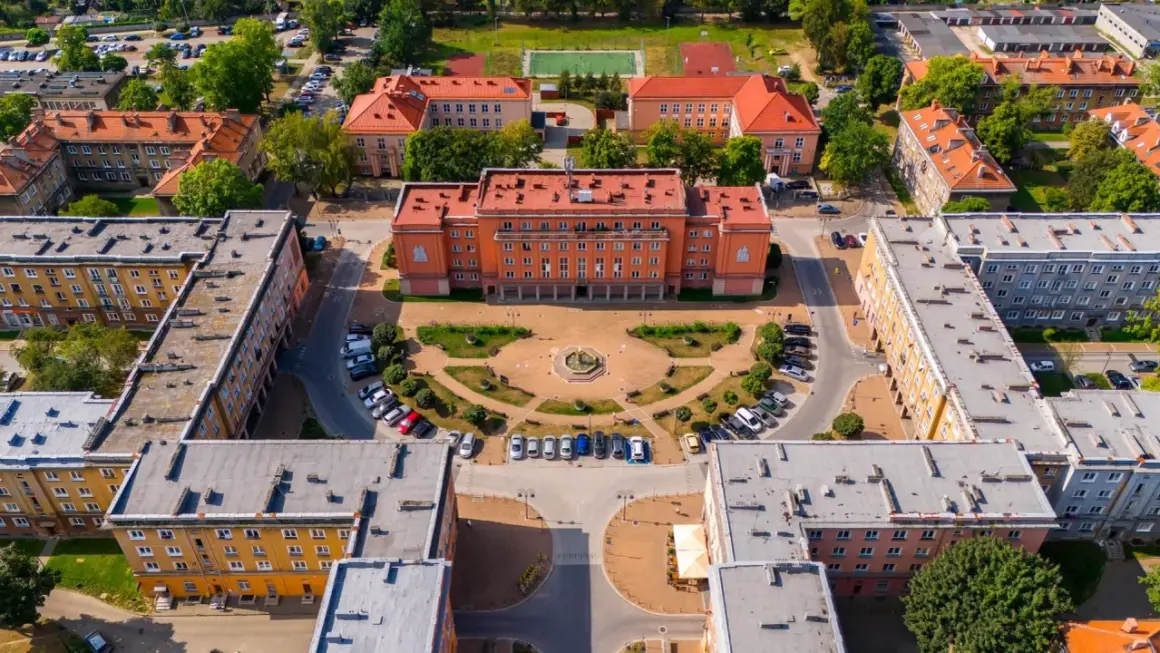 Osiedle Otylia w Tychach z lotu ptaka. Centralny budynek z pomarańczową fasadą, plac z fontanną i otaczające go bloki mieszkalne.