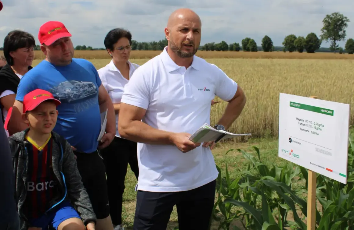 Grupa ludzi na polu kukurydzy, gdzie prezentowane są środki ochrony roślin, w tym metkonazol.