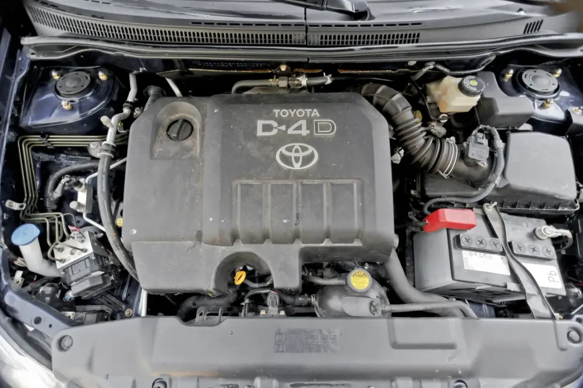 Silnik D-4D w Toyocie Corolla E12. Widoczny jest plastikowy kolektor dolotowy, akumulator i inne elementy komory silnika.