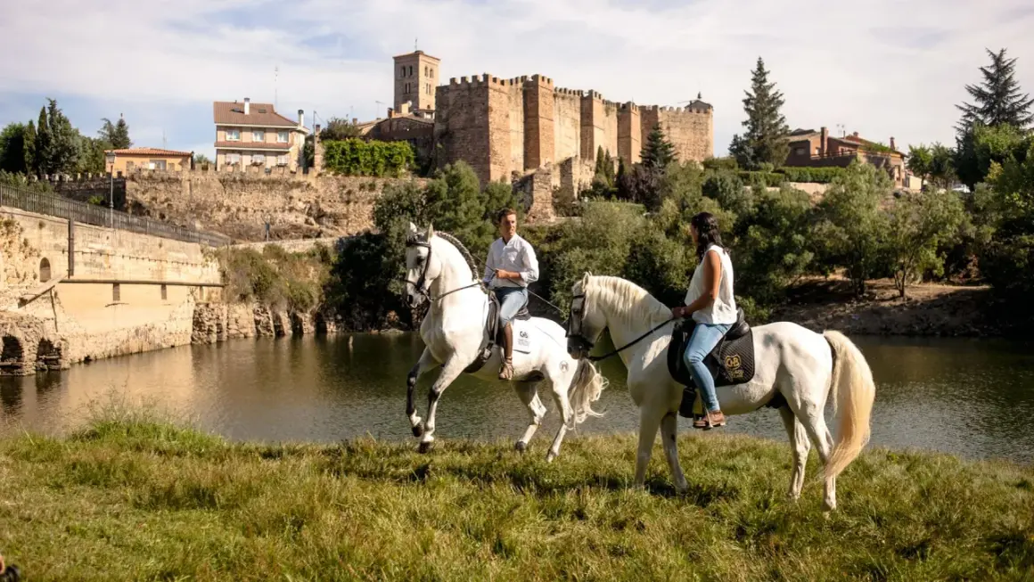 Paseo a caballo junto al río en Buitrago de Lozoya, con el castillo medieval al fondo.