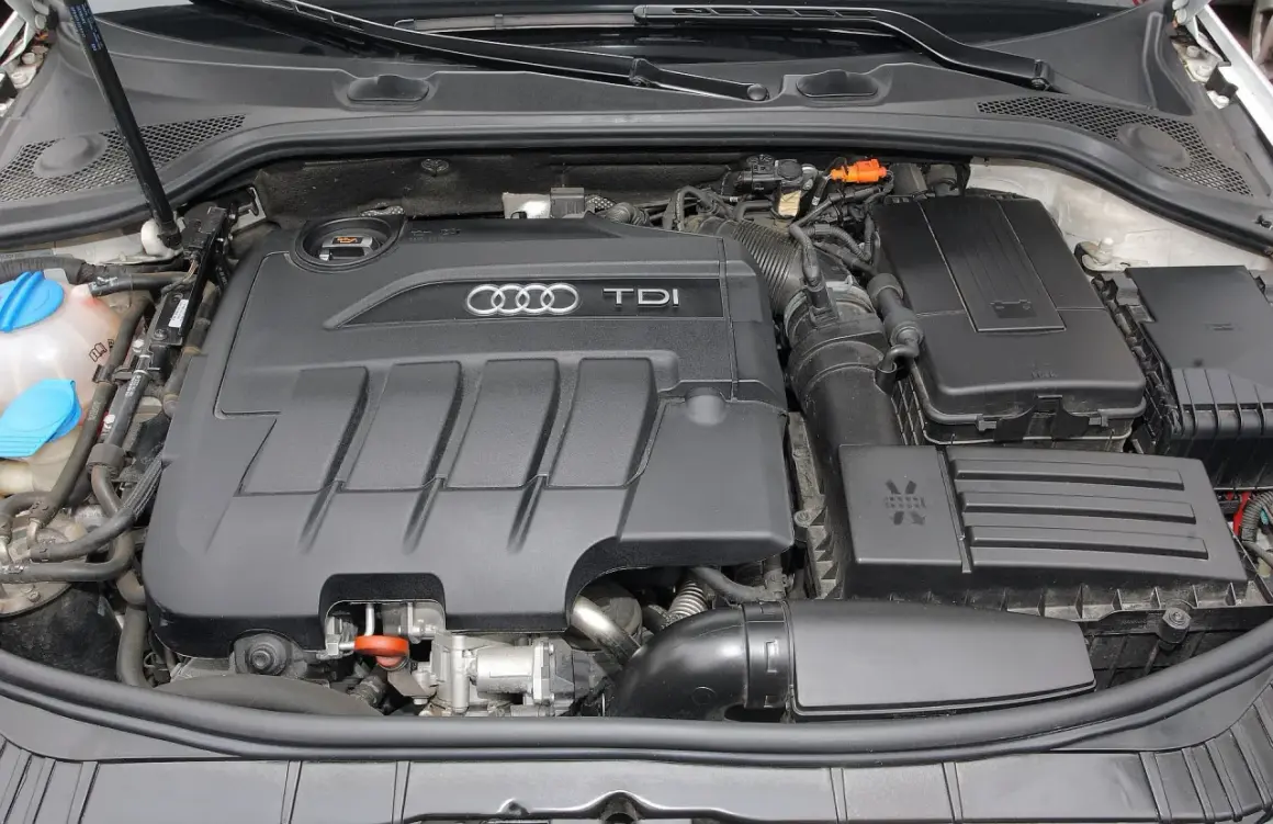 Silnik TDI w Audi A3. Widoczny czarny, plastikowy dekiel z logo Audi i napisem TDI.
