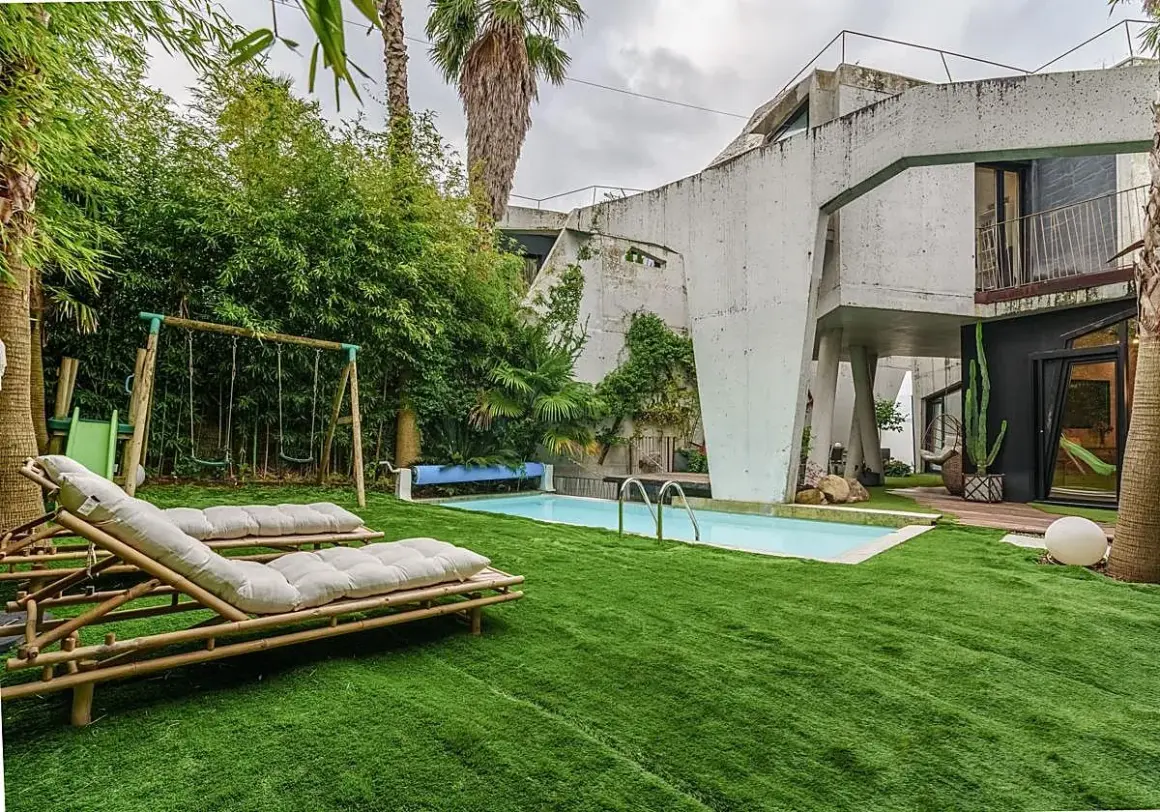 El jardín de la casa Sebastián San José invita al relax con tumbonas, piscina y columpios.