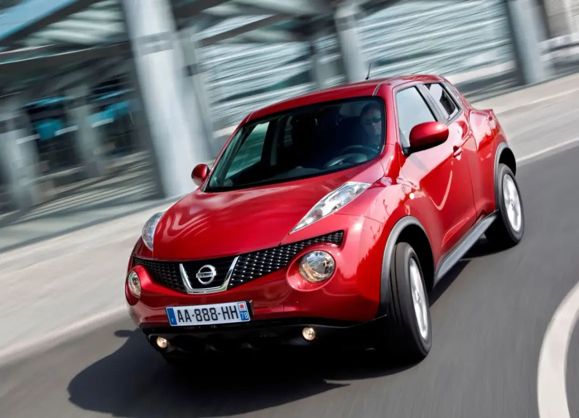 Czerwony Nissan Juke pędzi po drodze, jego dynamiczna sylwetka podkreślona przez ruch.