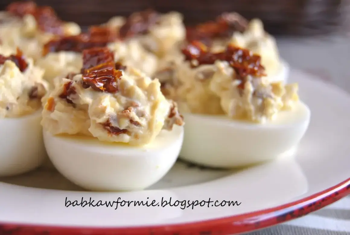 Pyszne jajka faszerowane suszonymi pomidorami, kremowym farszem i posypane kawałkami pomidorów.