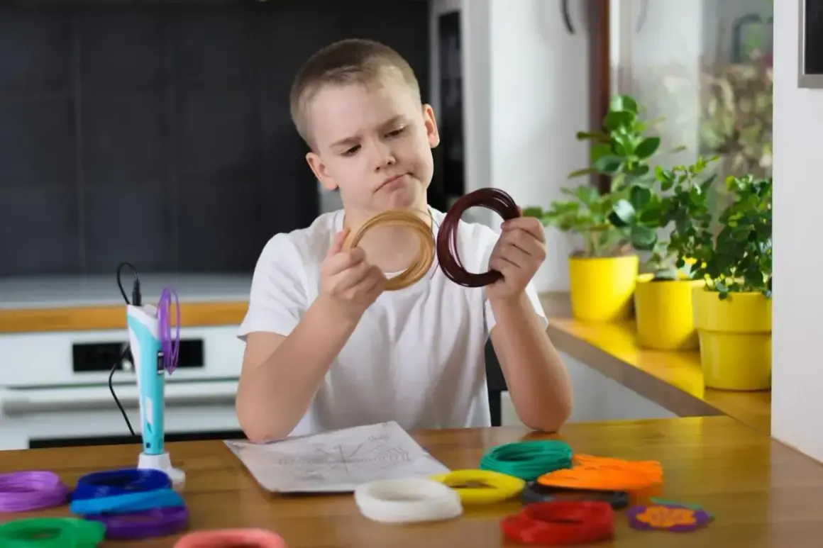 Chłopiec zastanawia się nad kolorami filamentów do drukarki 3D, wspierając swój rozwój sensoryczny.