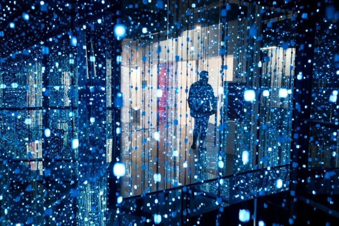Osoba wchodzi do instalacji świetlnej, jednego z nietypowych miejsc w Warszawie. Błękitne światła tworzą iluzję nieskończoności.