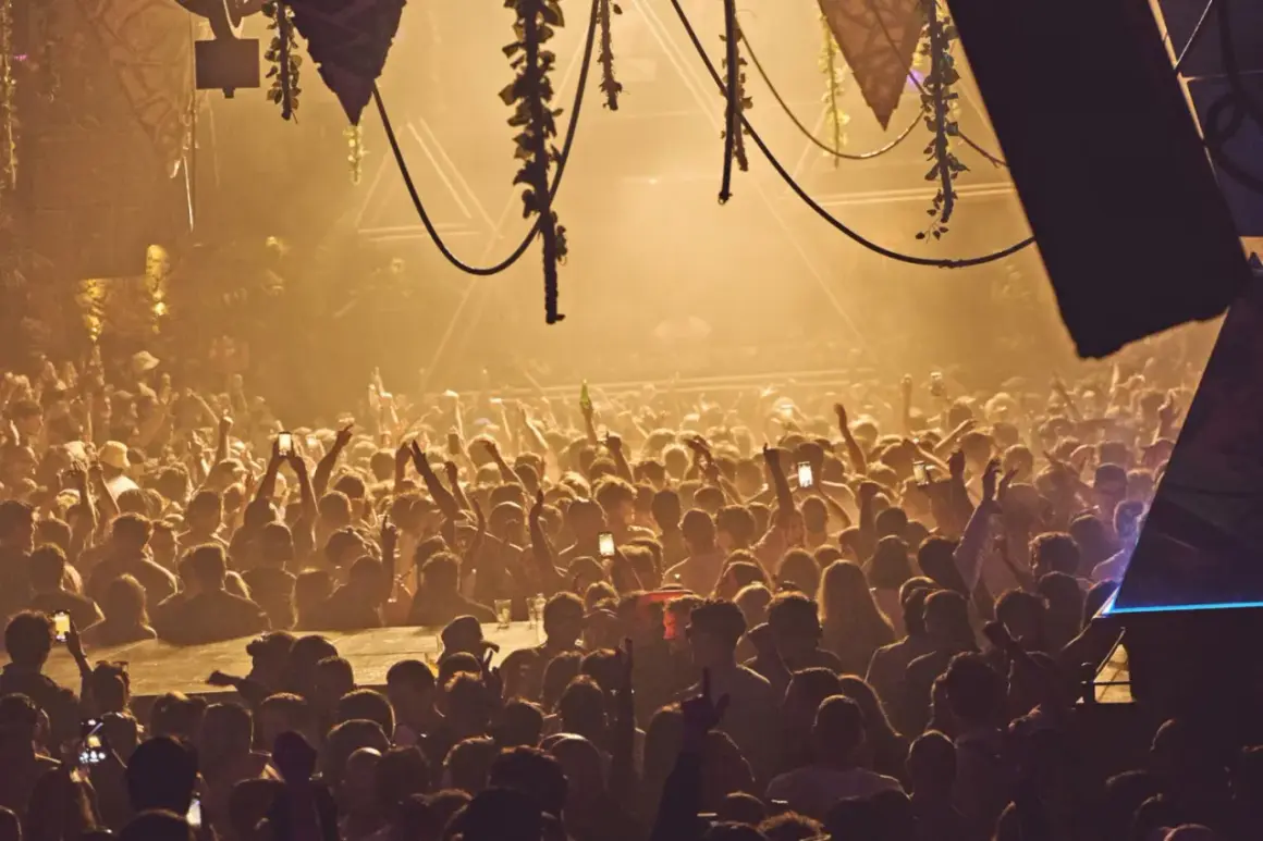 Folla in delirio all'Amnesia Ibiza, la capienza è al massimo. Luci soffuse e mani alzate in un'atmosfera elettrica.