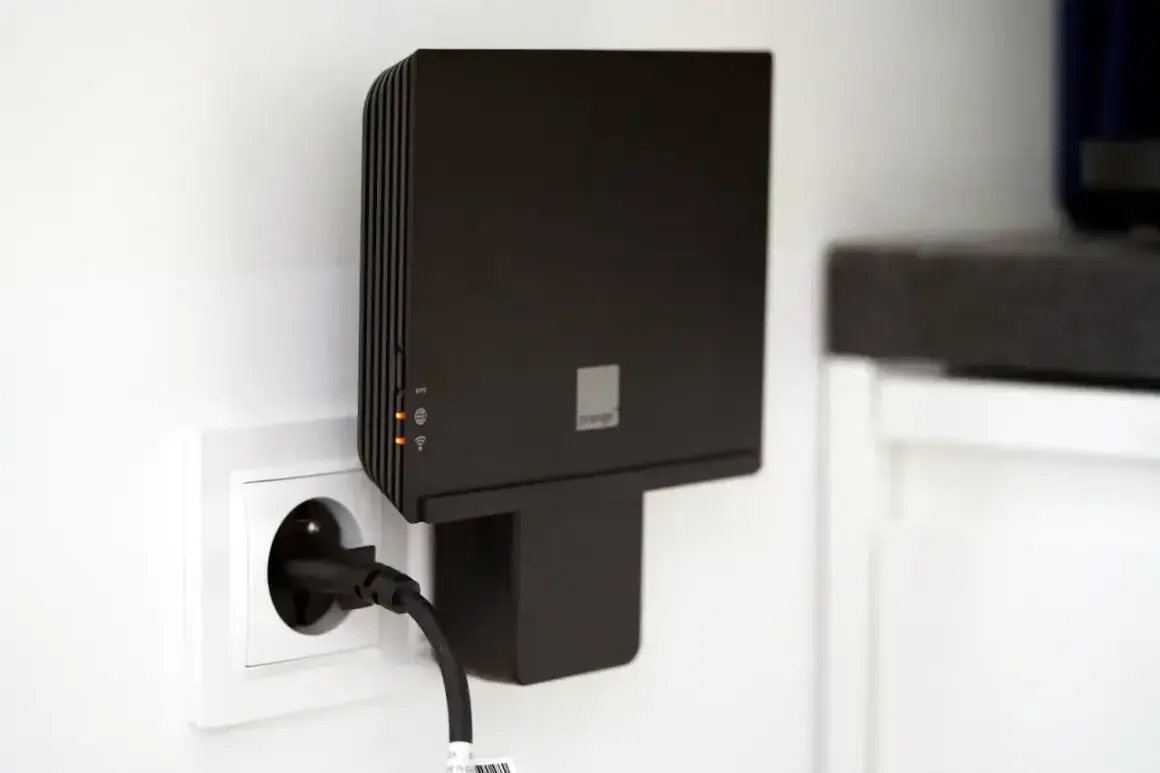 Czarny router Orange, model funbox 6, podłączony do gniazdka elektrycznego.