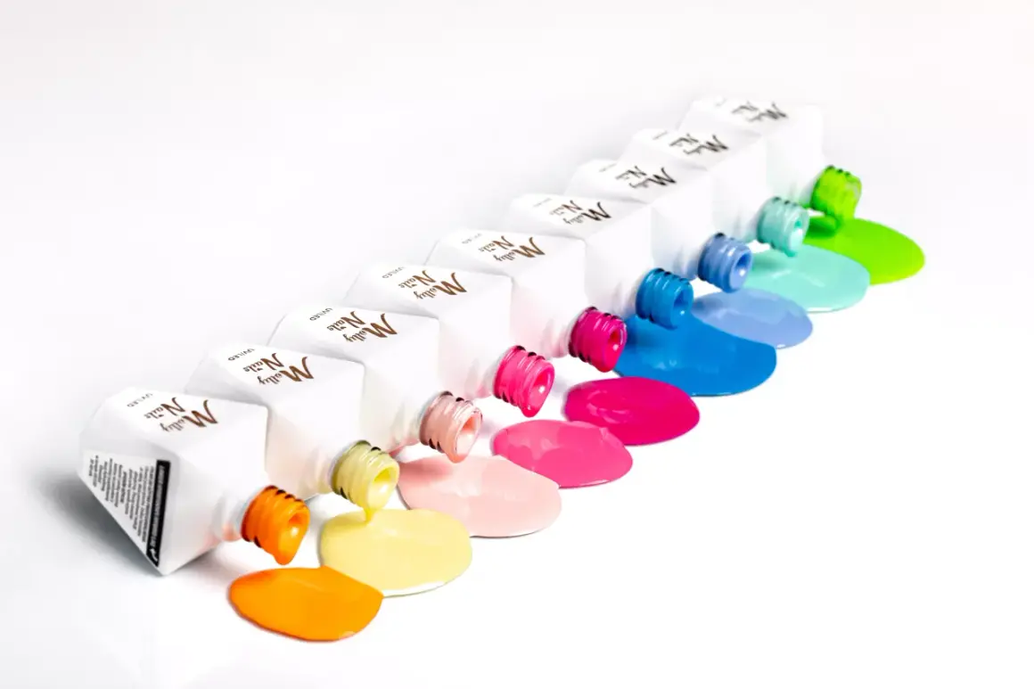 Kolorowe lakiery Molly Nails wylewają się z buteleczek, tworząc tęczowe plamy. Hema free co to znaczy? To bezpieczeństwo dla Twoich paznokci!