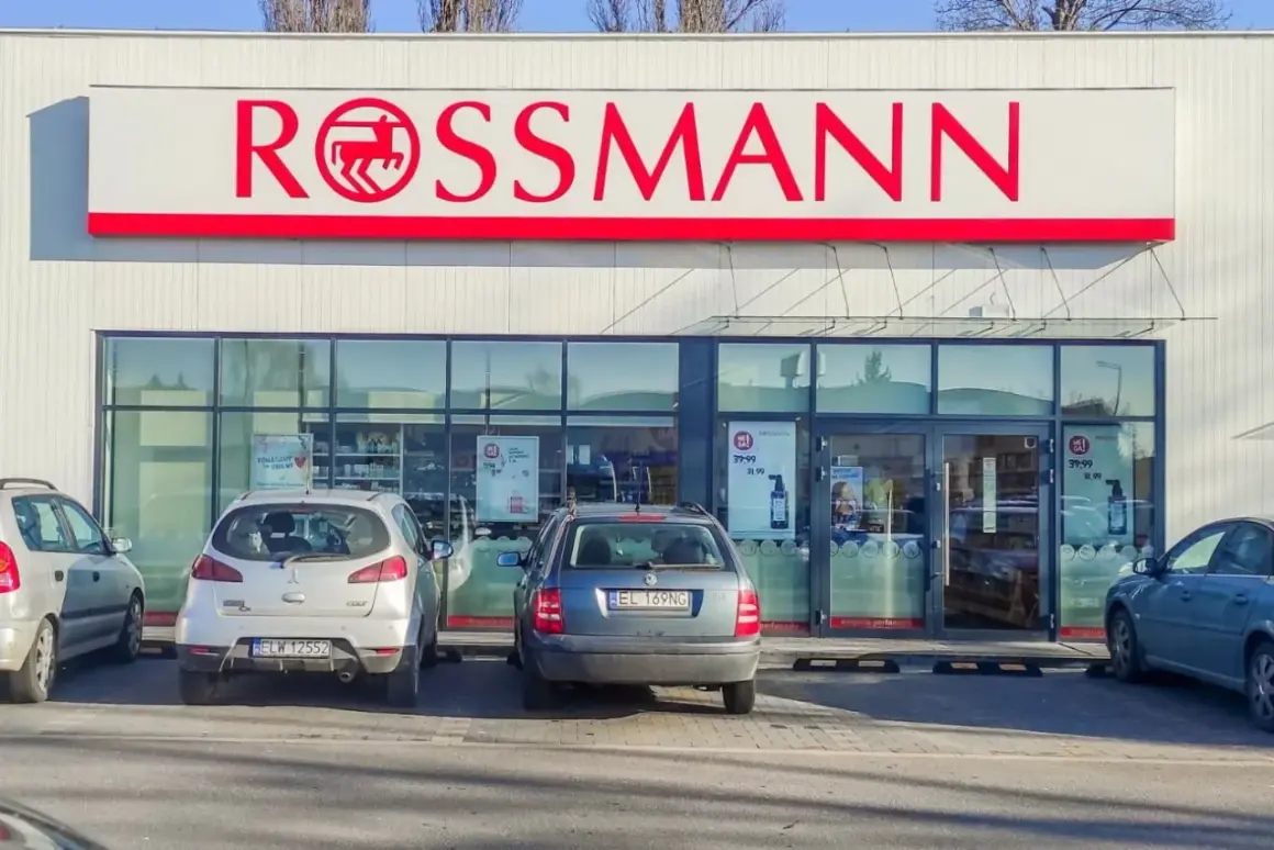 Elegancka fasada drogerii Rossmann z czerwonym logo i zaparkowanymi samochodami.