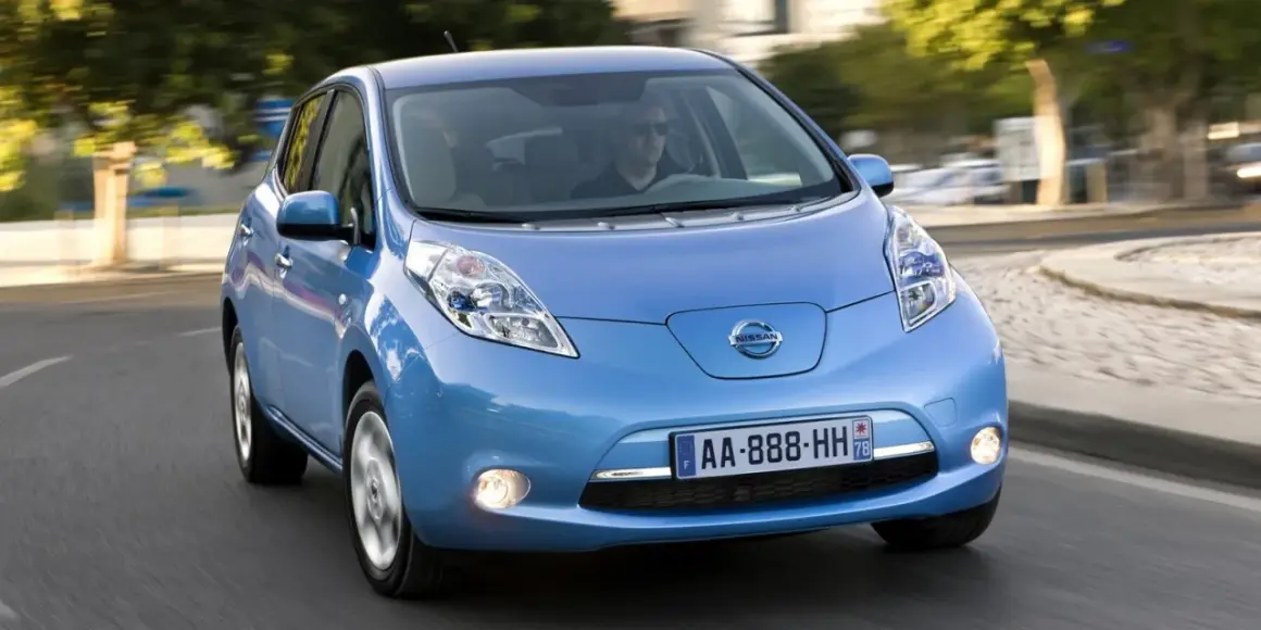 Un coche azul Nissan Leaf, uno de los coches mas fiables de segunda mano, circula por una carretera.