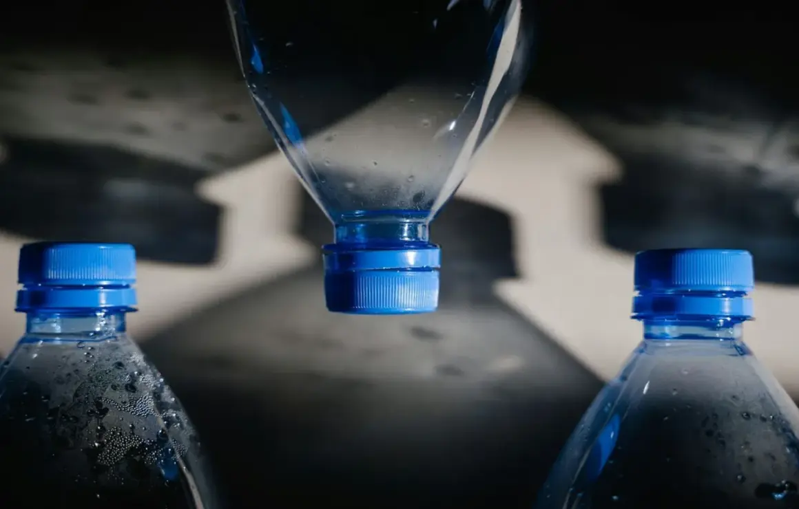 Bouteilles d'eau en plastique avec bouchons bleus. L'eau de Mont Roucous, une source d'eau naturelle, peut présenter un danger si elle est mal conservée.