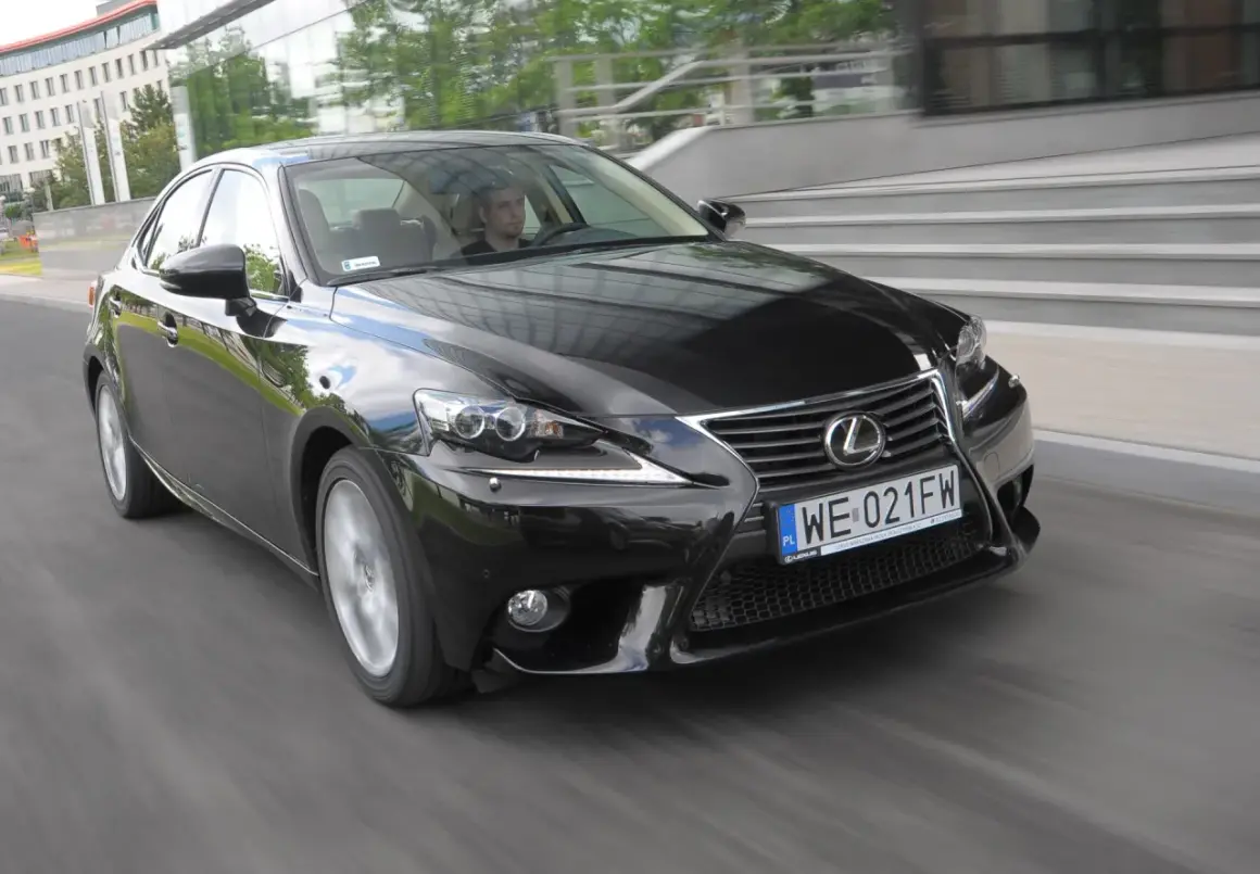 Czarny Lexus IS, doskonały wybór wśród lexusów używanych, pędzi ulicą. Kierowca wpatrzony w drogę.