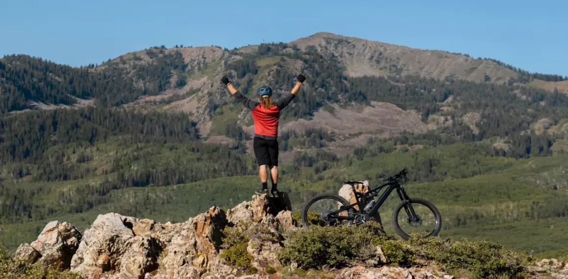 Ciclista celebra cima de montaña, listo para un camino de Santiago en bici con niños.