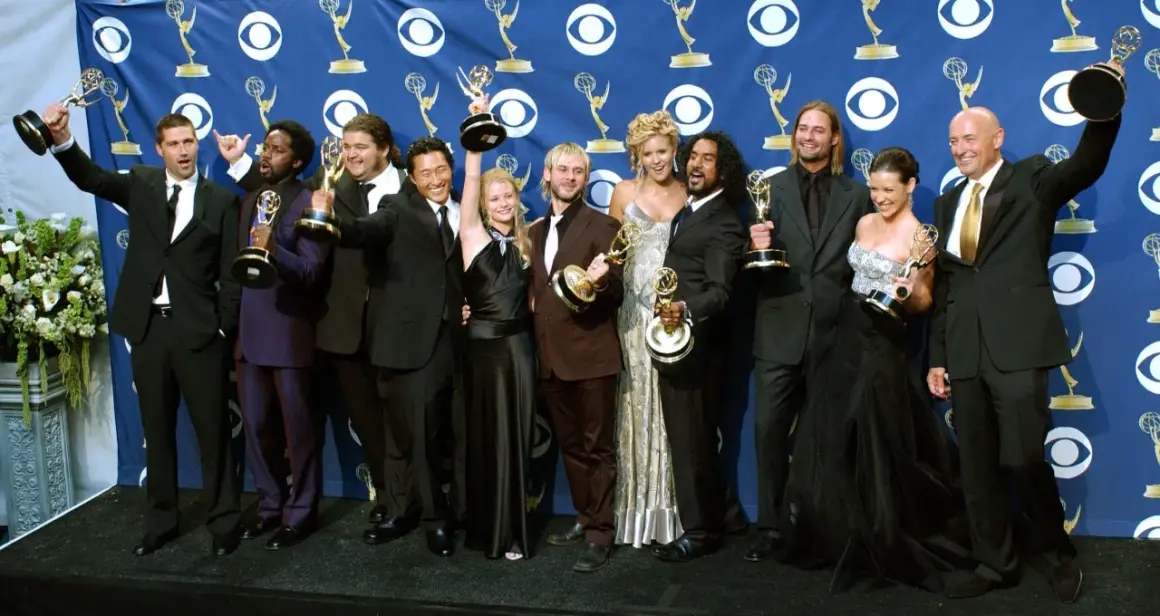 Die Besetzung von Lost feiert Emmy-Gewinne. Die Schauspieler posieren mit ihren Trophäen vor einem blauen Banner mit dem CBS-Logo.