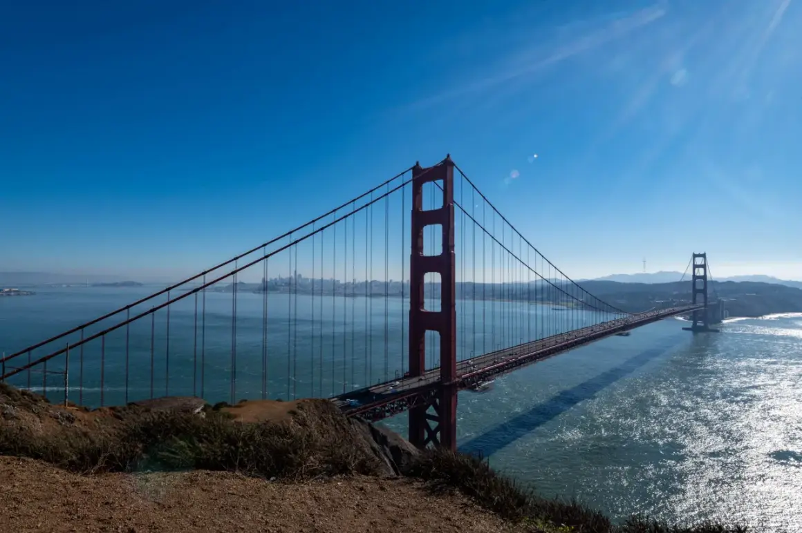 Ikoniczny most w San Francisco rozciąga się nad błękitną wodą, z miastem w oddali.