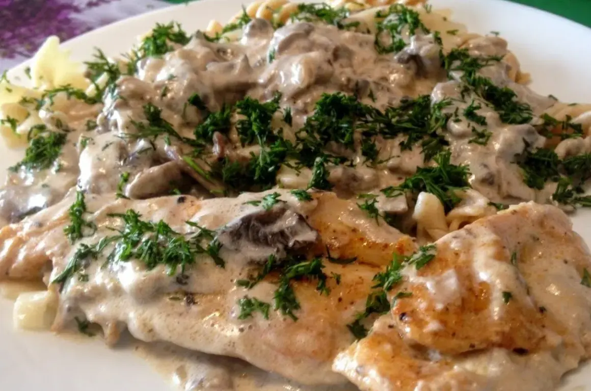 Kurczak z mascarpone i grzybami w kremowym sosie, podany z makaronem i posypany świeżym koperkiem.