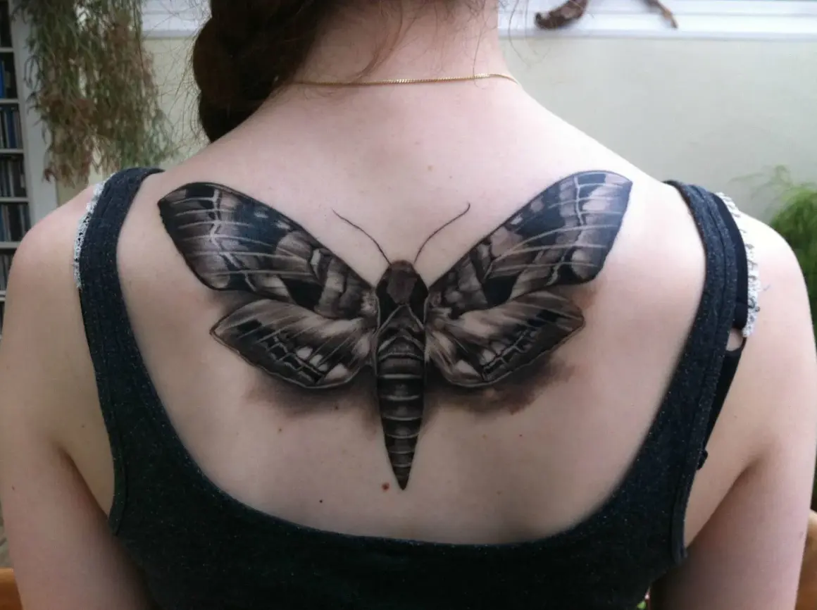 Realistyczny tatuaż ćmy na plecach. Ćma symbolizuje transformację, noc i tajemnicę.