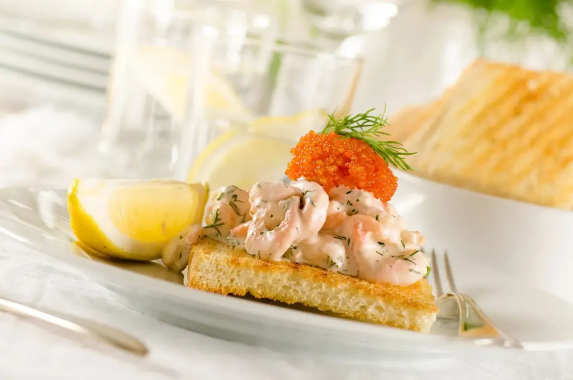 En perfekt toast skagen med krämiga räkor, rom och dill, serverad med citronklyfta. En riktig delikatess!