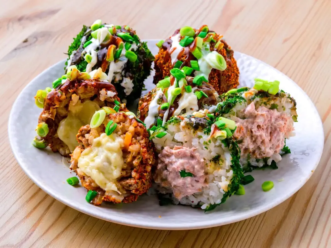 Sechs bunte Onigiri mit verschiedenen Füllungen und Toppings, umgeben von Frühlingszwiebeln und Saucen.