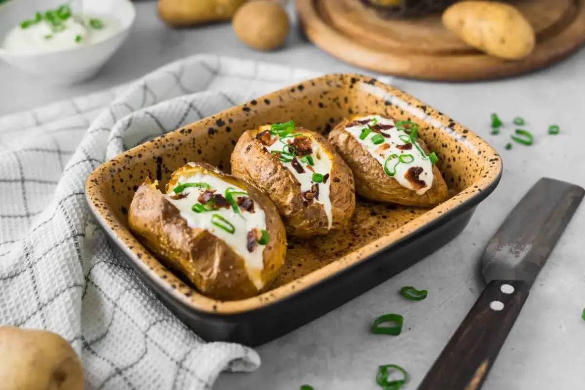 Drei gebackene Kartoffeln im Ofen, gefüllt mit Sour Cream und Speck. Garniert mit Schnittlauch.
