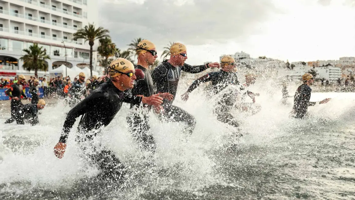 Sportler stürmen ins Wasser für einen Triathlon Kurzdistanz.