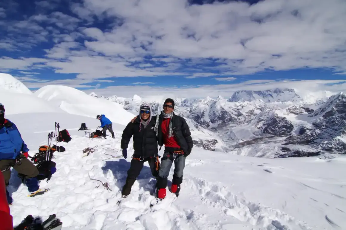 Dwóch alpinistów na śnieżnym szczycie Mera Peak, z zapierającym dech w piersiach widokiem na Himalaje.