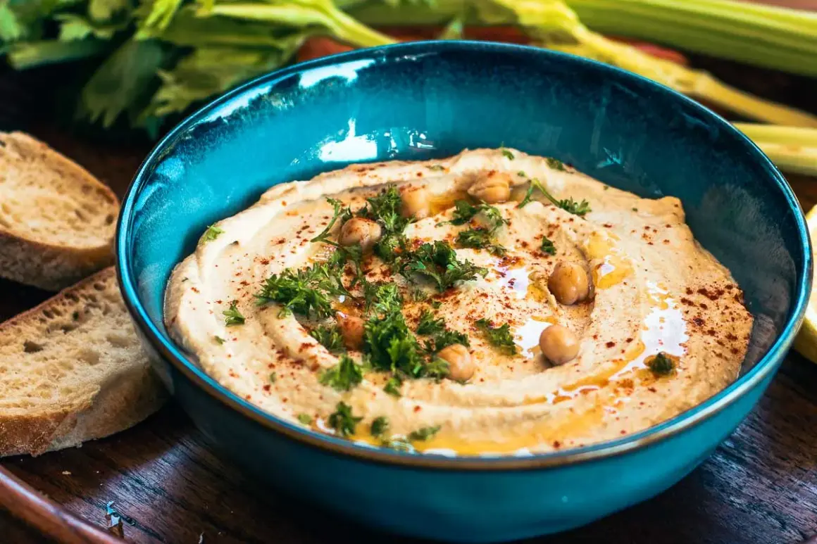 Cremiger Hummus mit Kichererbsen, Petersilie und Paprikapulver in einer blauen Schüssel, serviert mit Brot. Ein köstliches Hummus Rezept.