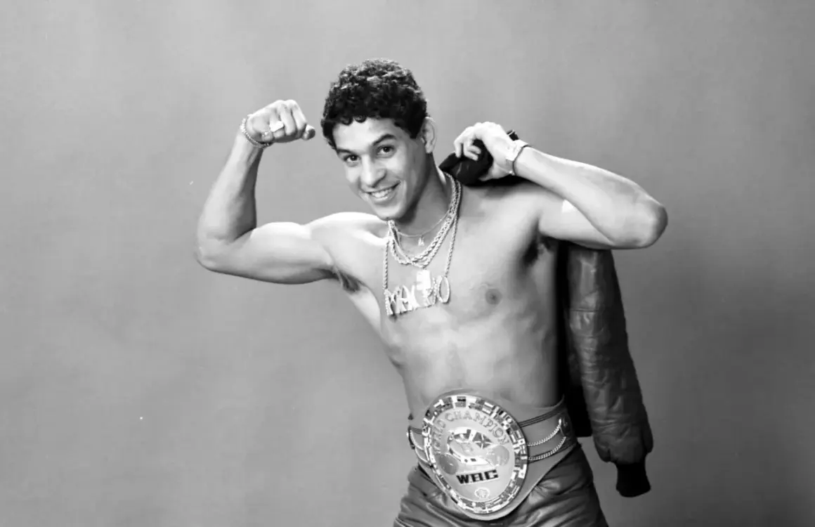 Boxaren Hector Camacho poserar stolt med sitt WBC-mästarbälte och en läderjacka över axeln.