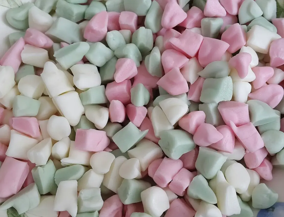 En hög med Ahlgrens bilar fluff i rosa, vitt och grönt. De ser mjuka och fluffiga ut, redo att ätas.