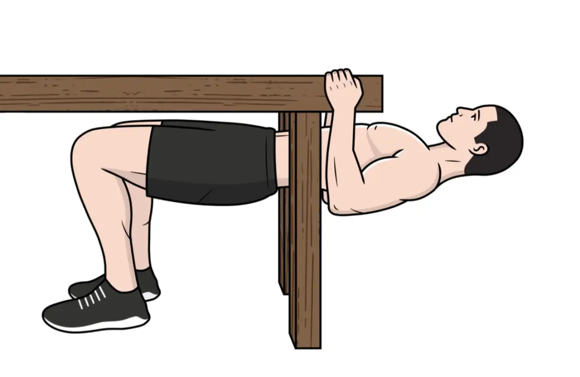 Homme faisant un exercice de traction biceps sous une table en bois, jambes pliées, pieds au sol.