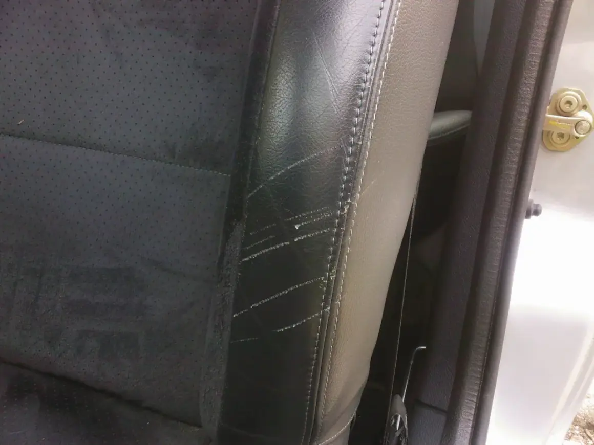 Siège de voiture en cuir noir avec des éraflures visibles, nécessitant une réparation de griffure cuir.