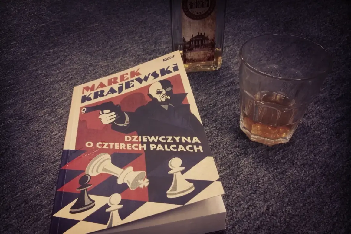 Powieść Marka Krajewskiego "Dziewczyna o czterech palcach" leży obok szklanki z bursztynowym trunkiem.