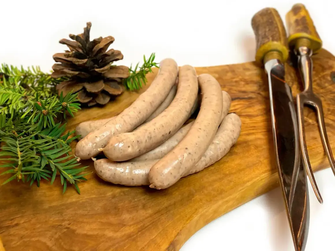 Kiełbasa z dzika na desce, z gałązkami iglaków i szyszką. Idealne jakie przyprawy do kiełbasy z dzika?