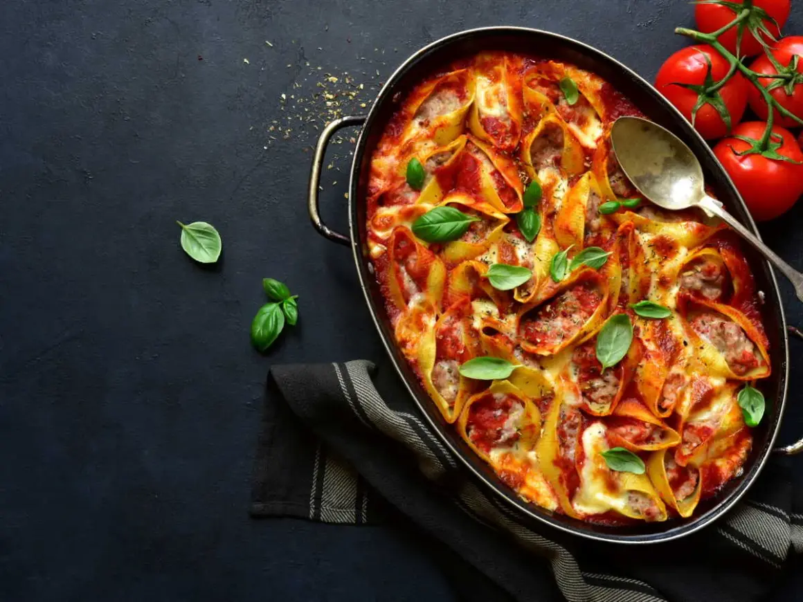Conchiglioni farcis à la sauce tomate et au fromage, prêts à faire lever la pâte au four. Garnis de basilic frais.