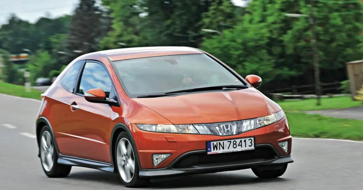 Pomarańczowy Honda Civic 8 tuning na drodze, z zielonymi drzewami w tle.