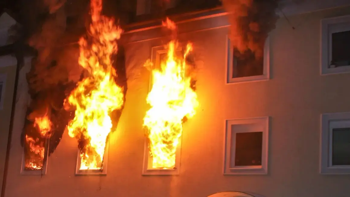 Flammen schlagen aus Fenstern eines Gebäudes. Dunkler Rauch steigt auf. Ein Beispiel für das richtige Verhalten im Brandfall ist die sofortige Evakuierung.