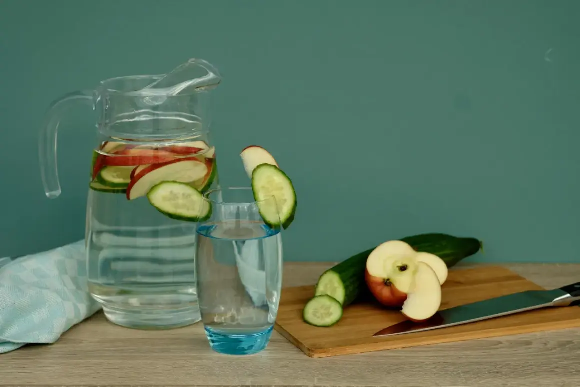 Erfrischendes Apfelwasser selber machen: Gurken- und Apfelscheiben in einer Karaffe und einem Glas.