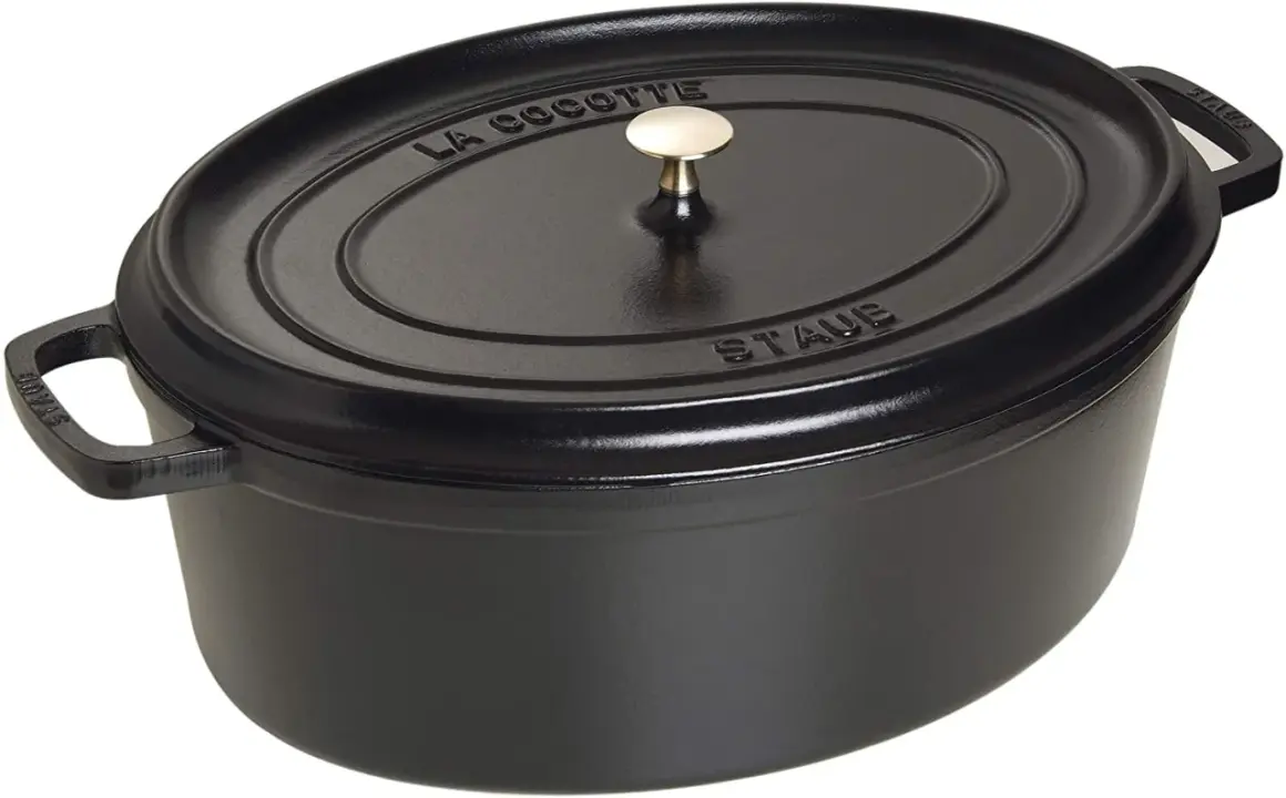 Schwarzer ovaler Schmortopf von Staub mit goldfarbenem Griff. Perfekt für langsam gegarte Gerichte, was ein Schmortopf eben ist.