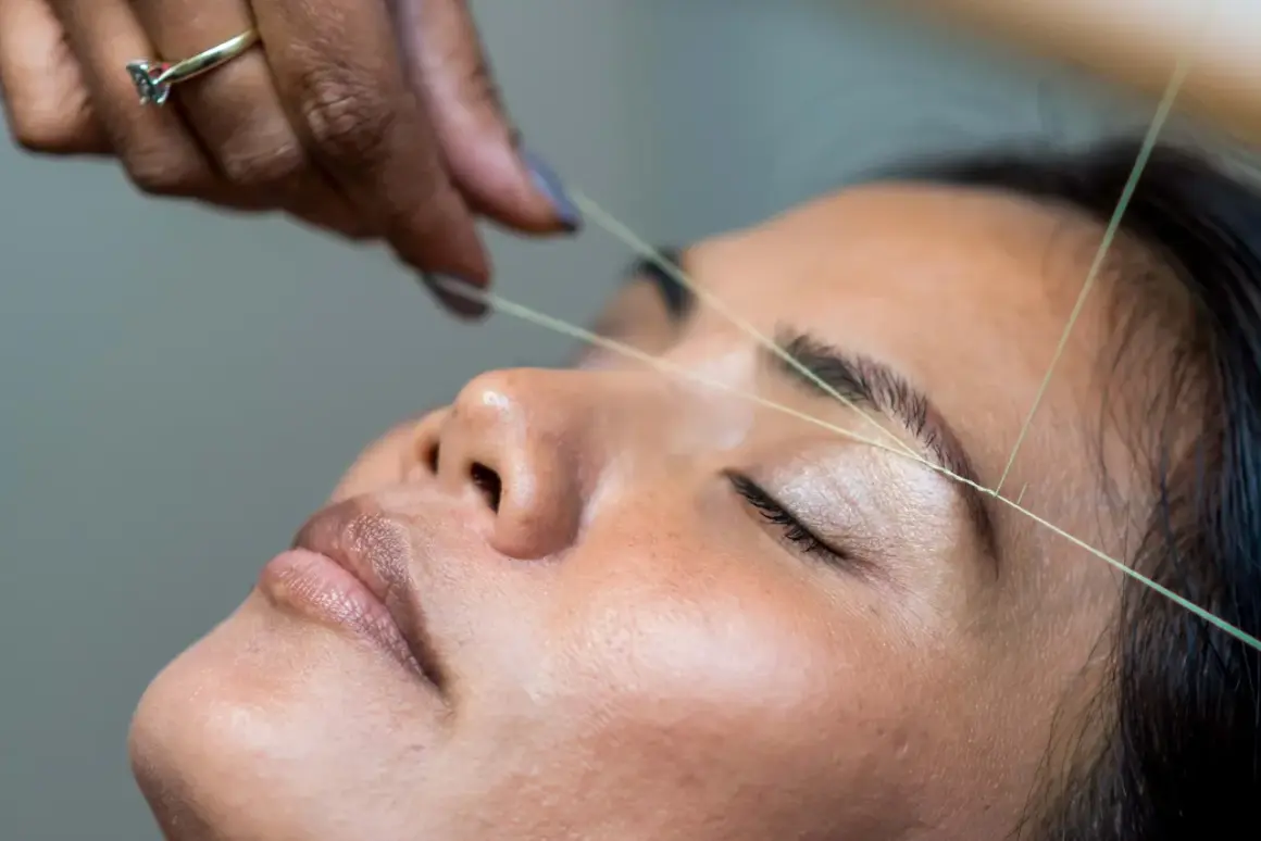 En tråd dras över ögonbrynet för att forma det, en klassisk brow bar-behandling som ger en perfekt brow bar mood.