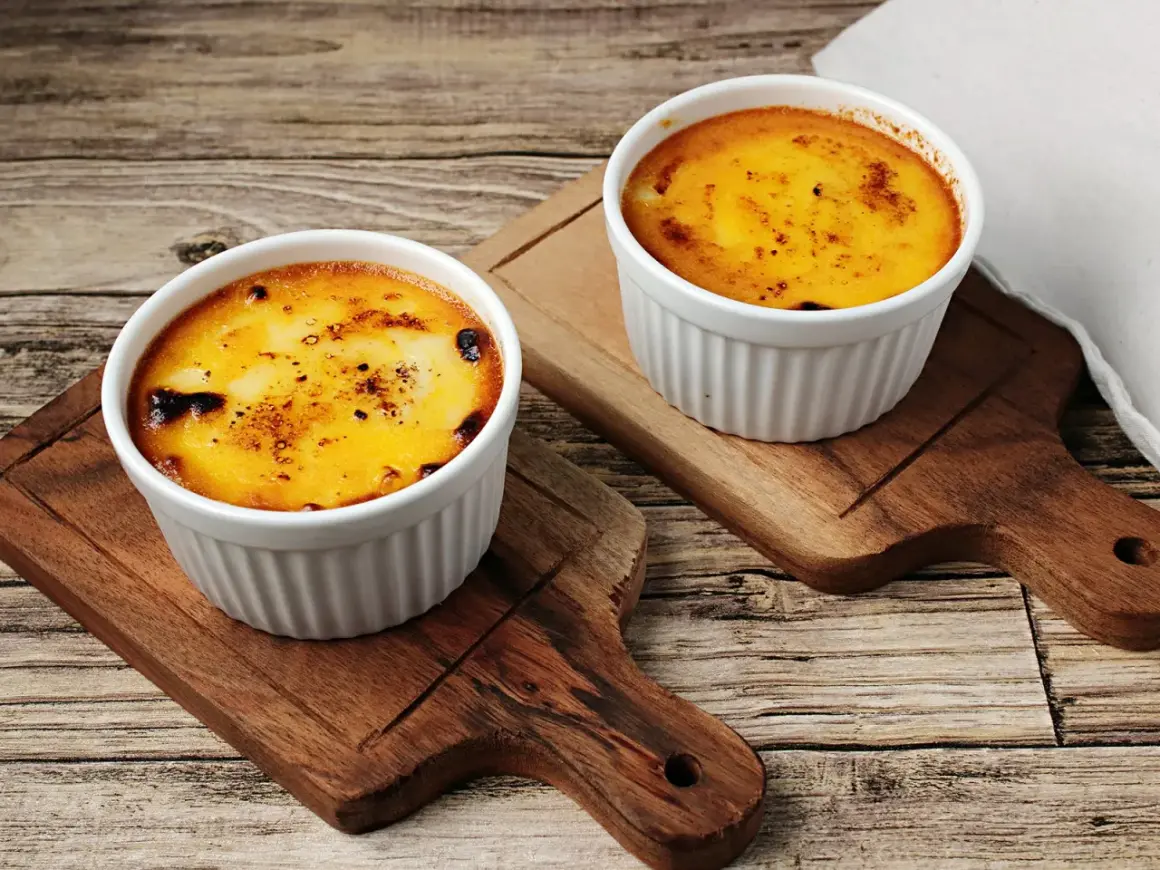 Zwei Portionen Crema Catalana Eis, karamellisiert und auf Holzbrettern serviert.