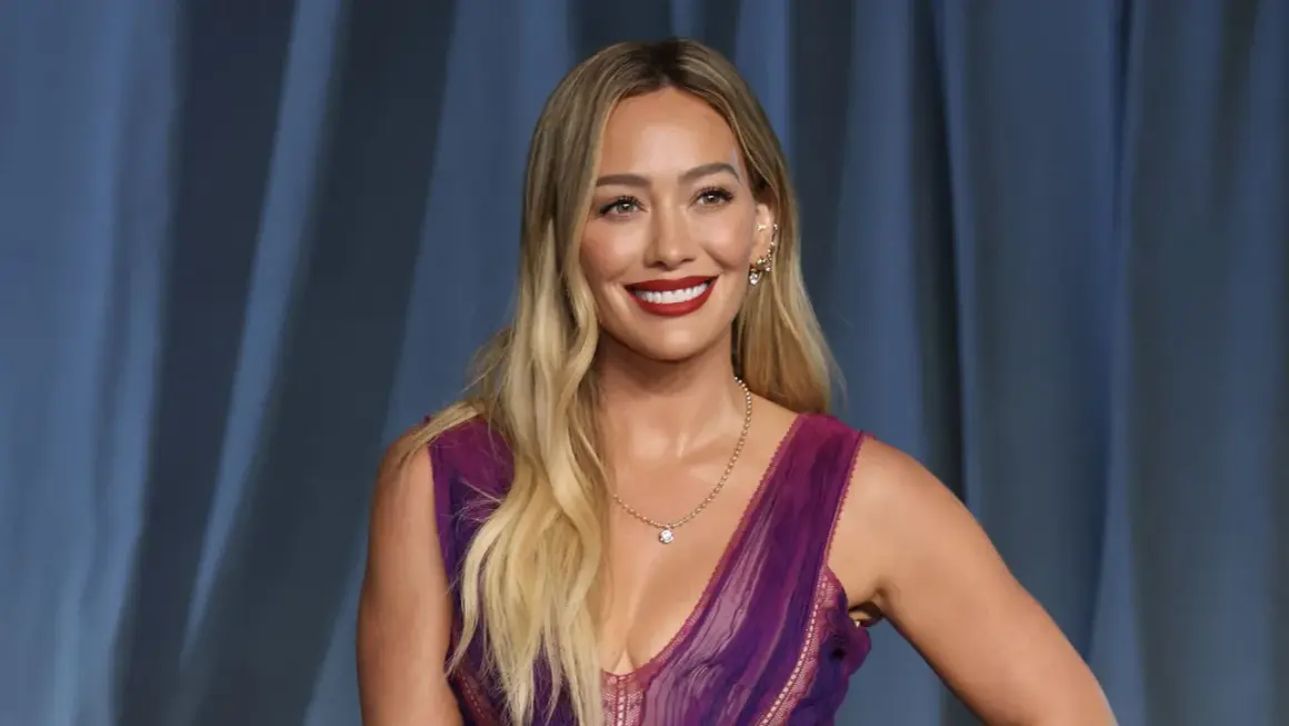 Hilary Duff, bekannt für ihre Filme und Serien, strahlt in einem lila Kleid.